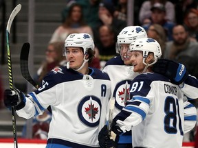Mark Scheifele, left, Jack Roslovic and Kyle Connor of the Winnipeg Jets celebrate a goal by Connor against the Colorado Avalanche in the third period at the Pepsi Center on Dec. 31, 2019, in Denver.