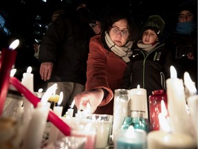 A family lights a candles together on a park bench turned shrine during a vigil for the victims of the Ukraine International Airlines flight in Montreal, on Thursday, January 9, 2020.