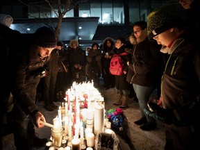 People light candles together on a park bench turned shrine during a vigil for the victims of the Ukraine International Airlines flight in Montreal, on Thursday, January 9, 2020.