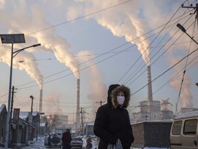 Smoke billows from stacks as a woman walks in a neighbourhood next to a coal-fired power plant on November 26, 2015 in Shanxi, China. "Make no mistake, when you buy something made in a country that relies heavily on electricity generated from coal, like China, you are contributing to carbonizing this planet," Robert Fattal writes.