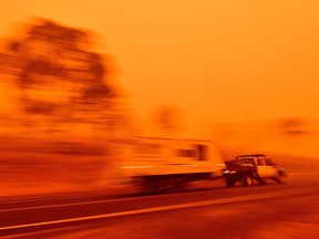 Residents commute on a road through thick smoke from bushfires in Bemboka, in Australia's New South Wales state on Sunday, Jan. 5, 2020.  Australians counted the cost from a day of catastrophic bushfires that caused "extensive damage" across swathes of the country and took the death toll from the long-running crisis to 24.