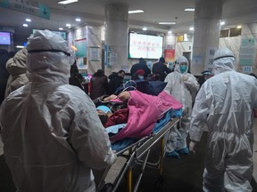 Medical staff wearing protective clothing to protect against a previously unknown coronavirus arrive with a patient at the Wuhan Red Cross Hospital in Wuhan.