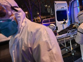 In this photo taken on January 25, 2020, medical staff wearing protective clothing to protect against a previously unknown coronavirus arrive with a patient at the Wuhan Red Cross Hospital in Wuhan. - The number of confirmed deaths from a viral outbreak in China has risen to 54, with authorities in hard-hit Hubei province on January 26 reporting 13 more fatalities and 323 new cases. (Photo by Hector RETAMAL / AFP)