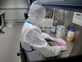 A laboratory operator handles patients' samples in a laboratory of the National Reference Center for respiratory viruses at the Institut Pasteur in Paris.
