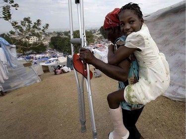 A girl smiles as her mother carries her down the sloping hills of the Petionville Golf Club in Port-au-Prince, Haiti, after being seen by a medic on January 26, 2010.