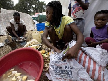 Widower Fanny Melisse, left, cleans fish as her 13-year-old daughter Anite Astelle, wearing a yellow shirt, helps her prepare dinner for her six children at the Petionville Golf Club in Port-au-Prince, Haiti, on January 26, 2010.