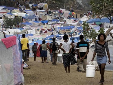 Fenise Pierre, 29, far right, carries a 5-gallon water bail up the slopes of the Petionville Golf Club in Port-au-Prince, Haiti, on January 26, 2010. The pail will weigh about 50 pounds once filled and she will wind her way back down to her tent.