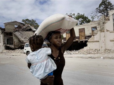 Darlene Andre carries her daughter and a 55-pound bag of rice as she leaves a UN food distribution centre in Port-au-Prince, Haiti, on January 26, 2010.
