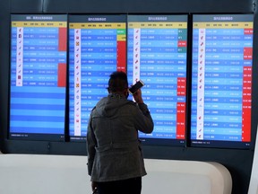 A man stands in front of a screen showing that multiple departure flights have been cancelled after the city was locked down following the outbreak of a new coronavirus, at an airport in Wuhan, Hubei province, China January 23, 2020.