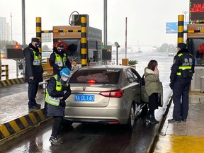 Police officers wearing masks check the boot of a car for smuggled wild animals at an expressway toll station following the outbreak of a new coronavirus, on the eve of the Chinese Lunar New Year celebrations in Wuhan, Hubei province, China, on Friday, Jan. 24, 2020.