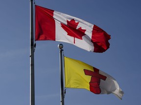 A Canada flag flies beside an Nunavut flag in Iqaluit, Nunavut on Wednesday, July 31, 2019. A new report on how police respond to violence against women in Canada's four northern Inuit regions says researchers have uncovered "systemic racialized policing" there.