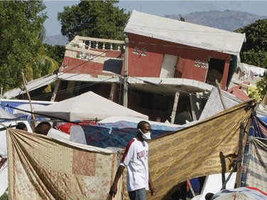 With damaged buildings in the background, a man walks through a camp for displaced persons at Parc Dadadou soccer field in Port-au-Prince, Haiti, on January 16, 2009, four days after a magnitude 7 earthquake hit the country.