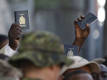 Haitians hoping to return to Canada hold up their Canadian passports as they wait in line at the Canadian embassy in Port-au-Prince on January 19, 2010.