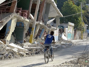 A boy rides past a collapsed house in Port-au-Prince, Haiti, on January 19, 2010.