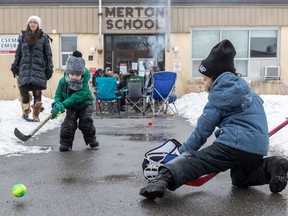 Five-year-olds Ethan Rosenshein, left, and goalie Ben Cytrynbaum pass the time Sunday in front of Merton School. Parents say the school should be included in a vaccination blitz being conducted by public health because the school is just a few blocks away from the designated zone.