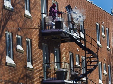 A woman clears snow from a balcony on Patricia Ave. in Montreal on Saturday, Feb. 8, 2020.