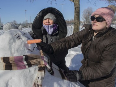 Any Riera (right) and her mother, Mery Violeta Ortiz, visiting from Venezuela, make a snowman at Loyola Park in Montreal on Saturday, Feb. 8, 2020.