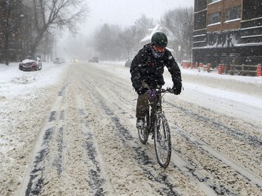 A cyclist rides on Sherbrooke St. W. Friday morning. Some roads were being cleared, but the city of Montreal announced Friday it will begin snow removal operations “progressively” at 7 a.m. Saturday.