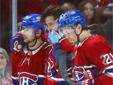 Montreal Canadiens Phillip Danault is helped off the ice by teammates Tomas Tatar, left, and Nick Cousins after getting hit in the mouth with a shot during second period of National Hockey League game against the Arizona Coyotes in Montreal Monday February 10, 2020.
