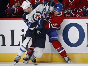 Montreal Canadiens' Nick Cousins is pinned against the boards by Winnipeg Jets defenceman Luca Sbisa as they fight for the puck in Montreal on Jan. 6, 2020.