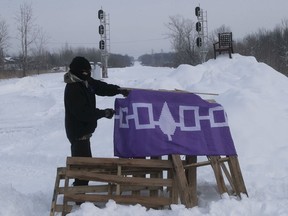 A protester puts up a flag on train track crossing Kahnawake on Feb. 11, 2020.