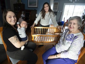 Rachelle Snow with her baby Santino left, Heidi May McFall centre, and Valerie McFall right, with the cradle woodworking students from former Riverdale and Pierrefonds Comprehensive high schools finished.