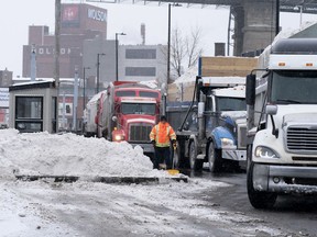 Trucks line up to unload snow into the sewer system at one of the approved dumps in Montreal, Feb. 13, 2020.