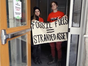 Divest McGill protestors Jordan Torbay, left, and Cailean Oikawa block a side entrance during the group’s occupation of McGill University’s Administration building on Tuesday. The group is calling on the school to divest its investments in two fossil fuel and also supports the Wet-suwet-en blockades of the gas pipeline in B.C., which has led to the Mohawk blockades affecting Quebec.