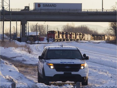 MONTREAL, QUE.: FEBRUARY 21, 2020 -- A CN police officer looks towards protesters blocking the CN railway tracks near the St-Lambert train station south of Montreal early Friday, Feb. 21, 2020. Behind is an idle freight train.