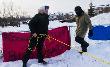 Eric St. Laurent yells at protesters blocking the CN railway tracks near the St-Lambert train station south of Montreal early Friday, Feb. 21, 2020 as he is approached by a protester while trying to take down a banner.