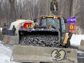 A payloader dumps large stones to reinforce concrete barriers installed on an access road that leads to a barricade as the Mohawks of Kahnawake continue their blockade of the CP Rail lines south of Montreal on Wednesday, February 26, 2020.
