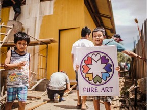 A  boy in Peru holds the Pure Art sign that will adorn the walls of his new home.