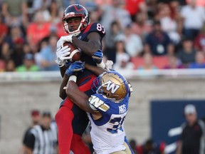 Montreal Alouettes' Eugene Lewis catches ball as he leaps over Winnipeg Blue Bombers' Marcus Rios during second half in Montreal on Sept. 21, 2019.
