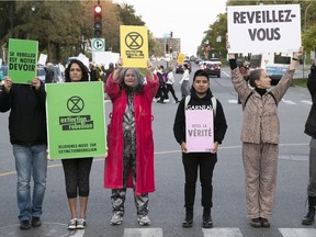 Climate change activists from Extinction Rebellion show their protest banners, as they stand in the middle of Parc Ave. on Wednesday October 9, 2019.