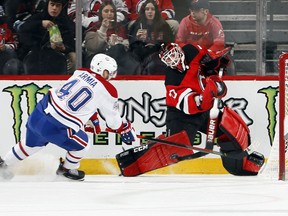 Devils goalie Louis Domingue clears the puck from behind the net as Canadiens' Joel Armia moves in on him during second period in New Jersey Tuesday night.