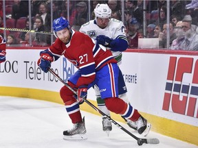 Canadiens' Karl Alzner  keeps the puck from Canucks' Tyler Toffoli during the first period Tuesday night at the Bell Centre.