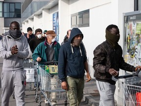 People wearing respiratory masks wait to be given a 10-minutes access to shop in a LIDL supermarket in groups of 20 people on Sunday, Feb. 23, 2020, in Casalpusterlengo, south-west Milan, Italy. Casalpusterlengo is one of the ten small towns placed under lockdown earlier this morning as a second death from coronavirus sparked fears throughout the Lombardy region.