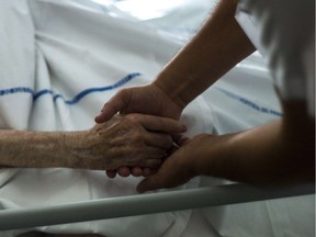 (FILES) A file picture taken on July 22, 2013 shows a nurse holding the hand of an elderly patient at the palliative care unit of the Argenteuil hospital, outside Paris. A panel set up at the request of President Francois Hollande on December 16, 2013 recommended legalising assisted suicide in France, where the debate on euthanasia has re-emerged after several end-of-life tragedies. The suicides of two elderly couples in November and the heartwrenching testimony of a politician who watched her terminally-ill mother die after taking pills have shocked and moved France, where euthanasia is illegal.AFP PHOTO / FRED DUFOURFRED DUFOUR/AFP/Getty Images ORG XMIT: POS1312161151512310 ORG XMIT: POS1504101413518393 // 1211 na euthanasia ORG XMIT: POS1511261852413923 ORG XMIT: POS1512101531173410  // 0517 col coyne