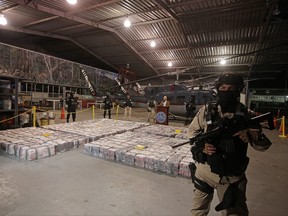 A police officer is seen in front of packages containing cocaine seized during an operation in the Caribbean, as Michael Soto, minister of Public Security, speaks to the media at the air base of the Ministry of Security in Alajuela, Costa Rica, un Saturday, Feb. 15, 2020.