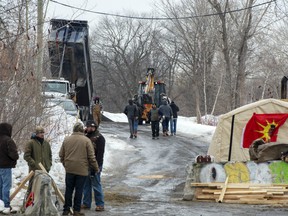 Members of the Mohawk community dump more gravel at the entrance to the blockade of the commuter rail line Wednesday, February 26, 2020 in Kahnawake, Que.