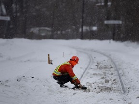A CP worker tests the tracks for signals after an AMT commuter train collided with a car at a level crossing on Gouin Blvd. in Montreal Feb. 18, 2020.