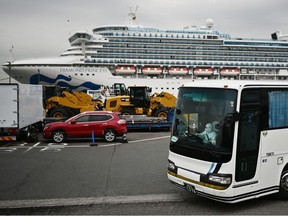 A bus with a driver wearing full protective gear departs from the dockside next to the Diamond Princess cruise ship, which has about 3,600 people quarantined onboard because of fears of the new COVID-19 coronavirus, at the Daikoku Pier Cruise Terminal in Yokohama port on Friday, Feb. 14, 2020.