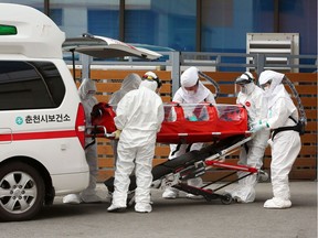 TOPSHOT - Medical workers wearing protective gear carry a patient infected with the COVID-19 coronavirus at a hospital in Chuncheon on February 22, 2020. - South Korea reported 142 more coronavirus cases on February 22, the sharpest spike in infections yet, with more than half of the new cases linked to a hospital in a southern city. The national toll of 346 is now the second-highest outside of China. (Photo by - / YONHAP / AFP) / - South Korea OUT / REPUBLIC OF KOREA OUT  NO ARCHIVES  RESTRICTED TO SUBSCRIPTION USE