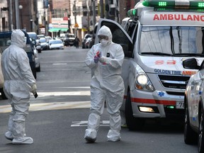 South Korean medical workers wearing protective gear carry samples as they visit a residence of people with suspected symptoms of the COVID-19 coronavirus, near the Daegu branch of the Shincheonji Church of Jesus in Daegu on February 27, 2020. - South Korea now has 1,766 cases, the highest number in the world outside China, where the disease first emerged in December and has since spread to dozens of countries. (Photo by Jung Yeon-je / AFP)