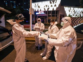 A volunteer distributes protective suits to others in Wuhan, China on February 26, 2020.