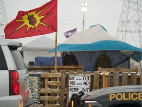 In this file photo taken on Feb. 26, 2020, Ontario Provincial Police and First Nations protestors sit on opposite sides of a barricade on Highway 6 near Caledonia, Ont., which the protesters set up, in support of the Wet'suwet'en hereditary chiefs and the Tyendinaga  Mohawks.