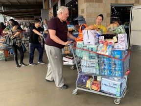 A man buys water, food and toilet paper at a store, as they begin to stockpile essentials from fear that supplies will be affected by the spread of the COVID-19, coronavirus, outbreak across the country, in Los Angeles on Saturday, Feb. 29, 2020.