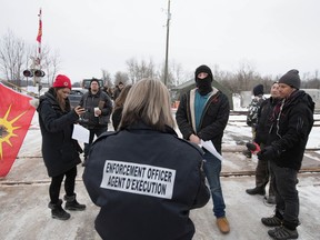 An Enforcement Officer reads the Injunction to members of the Tyendinaga Mohawk Territory in Tyendinaga Mohawk Territory, near Belleville, Ont., on Tuesday, Feb. 11, 2020, as they block the CN/VIA train tracks for a sixth day in support of Wet'suwet'en's blockade of natural gas pipeline in northern B.C.