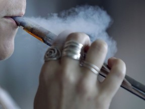 A woman using an electronic cigarette exhales a puff of smoke in Mayfield Heights, Ohio, in October 2019.