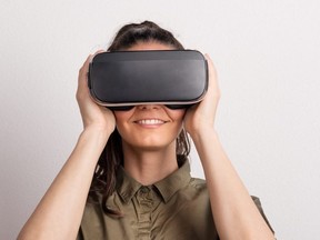 Portrait of a young beautiful woman with VR goggles in studio.